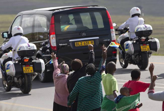 People wave goodbye as the funeral procession carrying the remains of former South African President Nelson Mandela proceeds to Mandela's hometown and burial site in Qunu, South Africa, on Saturday Dec. 14, 2013. The iconic leader will be buried on Sunday close to his house.