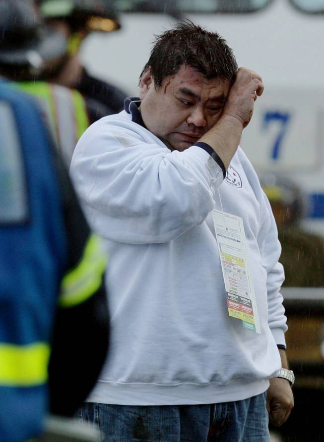 The driver of a tour bus wipes his face after the bus flipped on its side and crashed on wet southbound Interstate 15, half a mile north of the Ontario Avenue onramp, on Thursday, Dec. 19, 2013, in Corona, Calif. Three bus crashes on Thursday killed one person and injured dozens more as the vehicles crashed or overturned on rain-slick Southern California freeways, authorities said. (AP Photo/The Press-Enterprise, Terry Pierson)