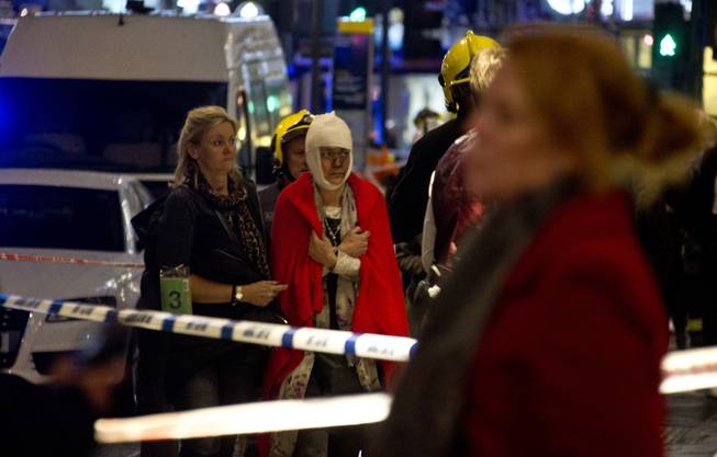 A woman stands bandaged and wearing a blanket given by emergency services following an incident at the Apollo Theatre, in London's Shaftesbury Avenue, Thursday evening, Dec. 19, 2013, during a performance at the height of the Christmas season, with police saying there were "a number" of casualties.