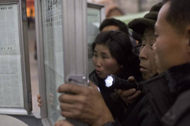 A North Korean man uses a flashlight as he and other subway commuters gather around a public newspaper stand on the train platform in Pyongyang, North Korea on Friday, Dec. 13, 2013 to read the headlines about Jang Song Thaek, North Korean leader Kim Jong Un's uncle who was executed as a traitor.