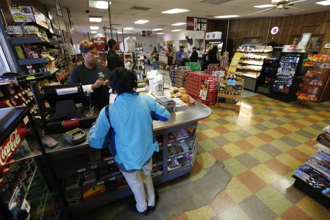 In this Dec. 23, 2013 photograph, cashiers tend to customers at Vine Brothers Quality Meats in Centreville, Miss. Bennie Vine, owner, is anxious for increased business the area's growing oil industry may provide, but is also cautious about enlarging his restaurant that is on the same block as his grocery store, butcher and deer meat processing facility and gas station.