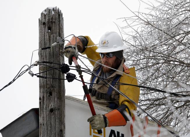 Cory Bean works atop a utility pole to repair a power line, Thursday, Dec. 26, 2013, in East Lansing, Mich. Bean is part of a crew from utility service company T&D Solutions out of Kentucky brought in to assist Consumers Energy with restoring power in Michigan after an ice storm. Bean has been working in Michigan since Sunday.