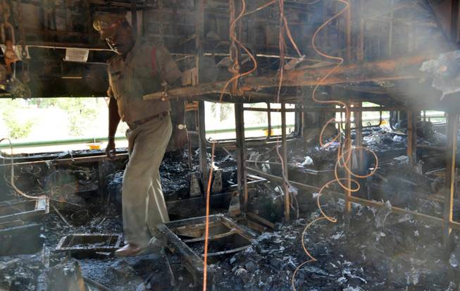 A policeman inspects the damage inside a train after a fire at Kothacheruvu, about 96 miles north of Bangalore, India, on Saturday, Dec. 28, 2013. A fire engulfed two coaches of an express train, killing at least two dozen people, many of whom became trapped and suffocated after the doors failed to open, officials said.