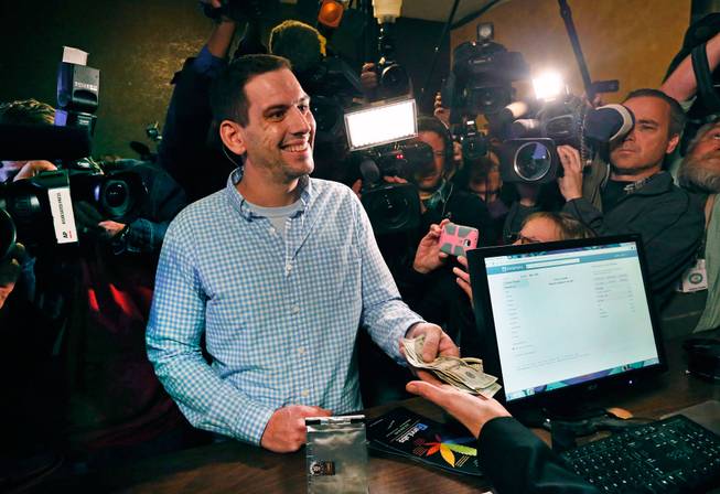 Sean Azzariti, a former Marine who served in the Iraq war and has post-traumatic stress disorder, smiles as he makes a cash transaction, the first to buy retail marijuana at 3D Cannabis Center, which opened as a legal recreational retail outlet in Denver, on Wednesday, Jan. 1, 2014. Colorado began retail marijuana sales on Jan. 1, a day some are calling "Green Wednesday."