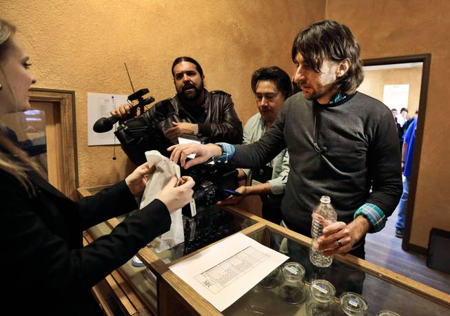 Customer Adam Hartle makes a cash transaction, one of the first to buy retail marijuana at 3D Cannabis Center, which opened as a legal recreational retail outlet in Denver, on Wednesday, Jan. 1, 2014. Colorado began retail marijuana sales on Jan. 1, a day some are calling "Green Wednesday."