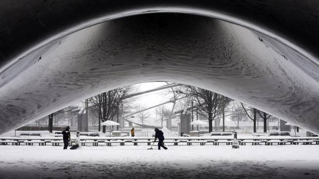 A park crew clears the snow around Annish Kapoor's stainless steel Cloud Gate sculpture at Millennium Park, Thursday, Jan. 2, 2014, as snow continues to accumulate in downtown Chicago. More snow could fall across the Chicago metro area Thursday, according to the National Weather Service.