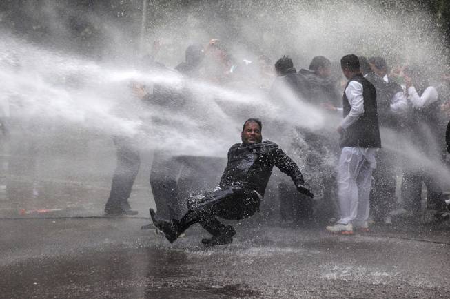 An activist of Indias main opposition Bharatiya Janata Party falls down as he and others are hit by police water cannon during a protest outside Congress party Vice President Rahul Gandhi's residence in New Delhi, India, Tuesday, Dec. 31, 2013. The protesters demand an explanation and action from Rahul Gandhi on charges of corruption against congress leader and Indian state of Himachal Pradesh chief minister Virbhadra Singh.
