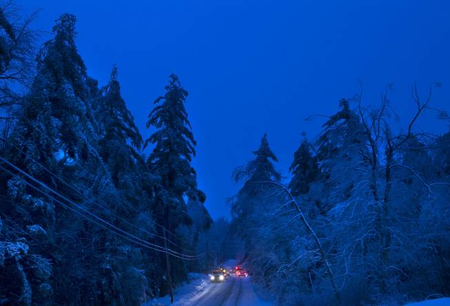 Utility crews prepare to work on power lines at dusk, Thursday, Dec. 26, 2013, in Litchfield, Maine, where many have been without electricity since Monday's ice storm. Up to 7 inches of snow is forecast, worrying utilities that the additional weight on branches and transmission lines could cause setbacks in the around-the-clock efforts to restore power.