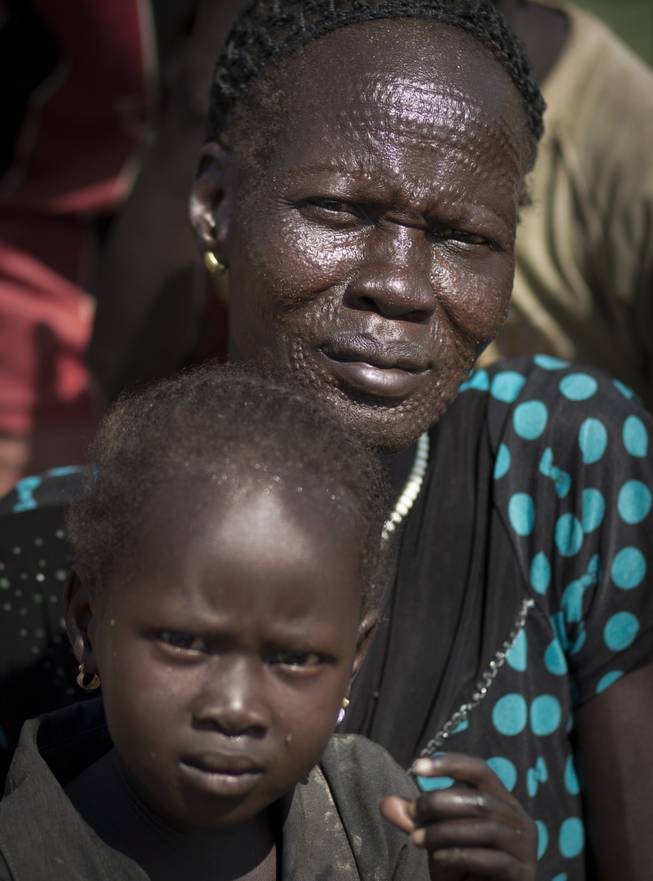 A displaced woman showing traditional scarification on her face sits with a child inside a United Nations compound which has become home to thousands of people displaced by the recent fighting, in Juba, South Sudan Friday, Dec. 27, 2013. Kenya's president Uhuru Kenyatta on Friday urged South Sudan's leaders to resolve their political differences peacefully and to stop the violence that has displaced more than 120,000 people in the world's newest country, citing the example of the late Nelson Mandela and saying there is "a very small window of opportunity to secure peace" in the country where fighting since Dec. 15 has raised fears of full-blown civil war.