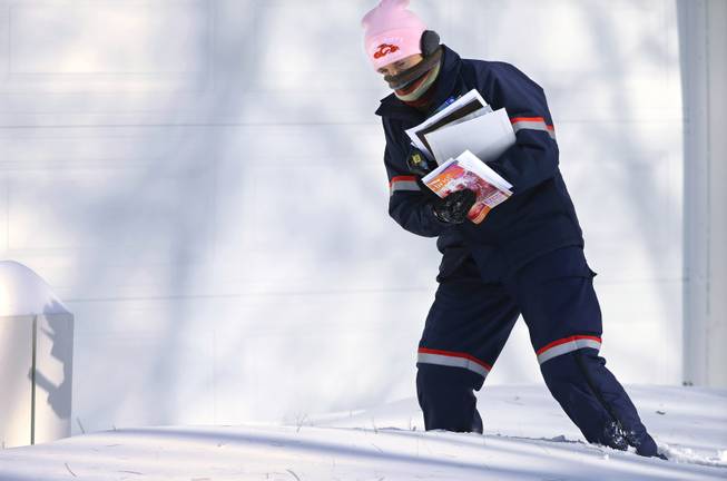 U.S. Postal Service letter carrier Jamie Jasmon struggles through snow and below zero temperatures while delivering the mail Monday, Jan. 6, 2014, in Springfield, Ill. A whirlpool of frigid, dense air known as a "polar vortex" descended into much of the U.S. and plunged temperatures to record lows.