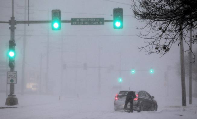 A Crestwood motorist tries to get his car moving along Watson Road in St. Louis as heavy snow falls on Sunday, Jan. 5, 2014. Snow-covered roads, high winds and ice were creating dangerous driving conditions from Missouri to Delaware on Sunday ahead of a "polar vortex" that'll bring below-zero temperatures not seen in years to much of the nation in the coming days, likely setting records.