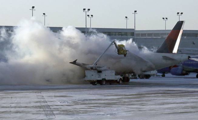 A Delta plane is deiced at Chicago Midway International Airport Monday, Jan. 6, 2014, in Chicago. The bitter weather comes after a heavy snowstorm hit much of the region last week. More than 1,000 flights were canceled Sunday at airports throughout the Midwest. More than 400 flights were cancelled at Chicago's airports Monday.
