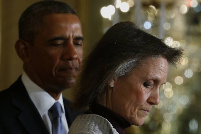 President Barack Obama listens as he is introduced by Katherine Hackett of Moodus, Conn., who receives unemployment insurance, before he spoke about what will happen if unemployment benefits are not extended, Tuesday, Jan. 7, 2014, in the East Room at the White House in Washington.