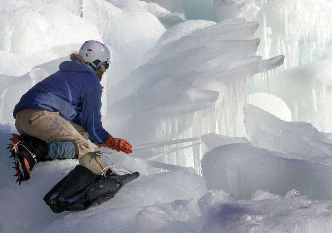 In this photo taken Wednesday Jan. 8, 2014 Cory Livingood places icicles on the top of his ice castle at the base of the Loon Mountain ski resort in Lincoln, N.H. The ice castle begins to grow in the fall when the weather gets below freezing and thousands of icicles are made and harvested then placed around sprinkler heads and sprayed with water. The castle will continue to grow as long as the temperatures stay below freezing.