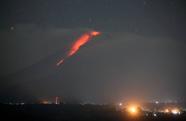 In this photo made with a slow shutter speed, hot lava flows from the crater of Mount Sinabung as seen from Gundaling, North Sumatra, Indonesia, early Thursday, Jan. 9, 2014. The volcano has sporadically erupted since September, forcing thousands of people who live around it slopes to flee their homes.