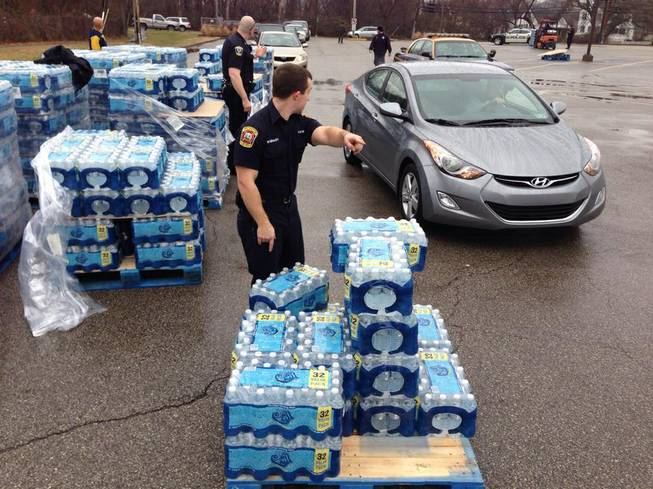 City officials help direct traffic through a water distribution site set up at the South Charleston Recreation Center in South Charleston, W.Va., Friday, Jan. 10, 2014, after at least 100,000 customers in nine West Virginia counties were told not to drink, bathe, cook or wash clothes using their tap water because of a chemical spill into the Elk River in Charleston, with Gov. Earl Ray Tomblin declaring a state of emergency Thursday for all those areas. The site opened before 9 a.m. with bottled water and a tanker truck, but was expected to run out of water about 90 minutes later.