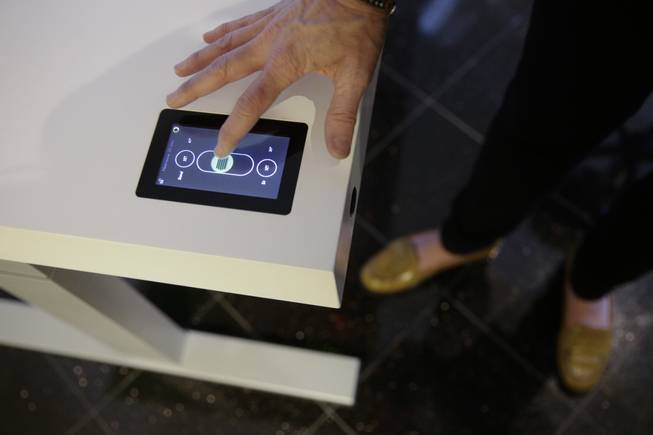 Jennifer McNally, a head of marketing at Stir, demonstrates on the Kinetic Desk at the International Consumer Electronics Show on Wednesday, Jan. 8, 2014, in Las Vegas. With built-in motorized legs, the hight of the desk can be adjusted by using a touchscreen controller located in the corner of the desk.