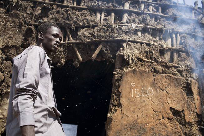 Ash drifts into the face of David Luo Kuang, 18, as he stands outside the doorway of his still-smoldering home that was burned in the recent fighting, after government forces on Friday retook from rebel forces the provincial capital of Bentiu, in Unity State, South Sudan, Sunday, Jan 12, 2014. On Sunday senior South Sudanese government officers inspected the recaptured town of Bentiu, in northern Unity State, that was the scene of intense fighting between government and rebel forces, while a South Sudanese government official claimed rebels had badly damaged petroleum facilities in the state.