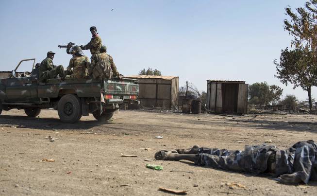 South Sudanese government forces drive past the body of a rebel soldier, after government forces on Friday retook from rebel forces the provincial capital of Bentiu, in Unity State, South Sudan, Sunday, Jan 12, 2014. On Sunday senior South Sudanese government officers inspected the recaptured town of Bentiu, in northern Unity State, that was the scene of intense fighting between government and rebel forces, while a South Sudanese government official claimed rebels had badly damaged petroleum facilities in the state.