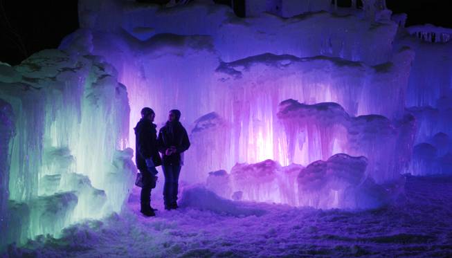 In this photo taken Wednesday Jan. 8, 2014 patrons tour an ice castle at the base of the Loon Mountain ski resort in Lincoln, N.H. The ice castle begins to grow in the fall when the weather gets below freezing and thousands of icicles are made and harvested then placed around sprinkler heads and sprayed with water.