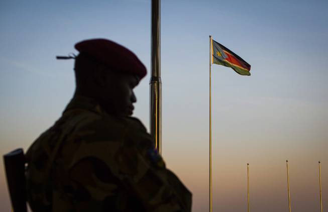 A South-Sudanese government soldier stands guard as a South Sudanese flag flies in the background, at the memorial to politician and leader John Garang who died in a helicopter crash in 2005, in Juba, South Sudan Monday, Jan 13, 2014. Despite the appearance of diplomatic progress, more violence in the country looks possible, and by boat and truck South Sudan troops are moving in on Bor which is currently held by rebels.