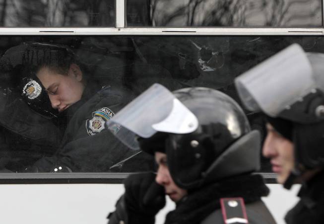 A police officer sleeps in a police van near of the Ukrainian Parliament in Kiev, Ukraine, in Kiev, Ukraine, Tuesday, Jan. 14, 2014. Organizers of the weeks-long anti-government protests are looking for a future strategy amid dwindling numbers and a continuing government crackdown on the protesters. The demonstrations, known as Euromaidan, were sparked by President Viktor Yanukovych's decision in November to freeze ties with the West and tilt toward Moscow. The pact was later sealed by a $15 billion bailout loan from the Kremlin.