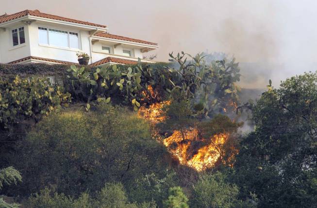 A fast moving wildfire makes it way up a hill towards a house in the hills just north of the San Gabriel Valley community of Glendora, Calif. on Thursday, Jan 16, 2014. Southern California authorities have ordered the evacuation of homes at the edge of a fast-moving wildfire burning in the dangerously dry foothills of the San Gabriel Mountains.