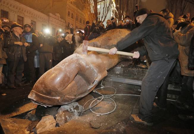Ukrainian protesters smash a statue of Vladimir Lenin with a sledgehammer after toppling it, in central Kiev, Ukraine, Sunday, Dec. 8, 2013. The third week of protests continue Sunday with an estimated 200,000 Ukrainians occupying central Kiev to denounce President Viktor Yanukovychs decision to turn away from Europe and align this ex-Soviet republic with Russia.