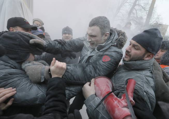 Opposition leader and former WBC heavyweight boxing champion Vitali Klitschko, center, is attacked and sprayed with a fire extinguisher as he tries to stop the clashes between police and protesters in central Kiev, Ukraine, Sunday, Jan. 19, 2014. Hundreds of protesters on Sunday clashed with riot police in the center of the Ukrainian capital, after the passage of harsh anti-protest legislation last week seen as part of attempts to quash anti-government demonstrations. A group of radical activists began attacking riot police with sticks, trying to push their way toward the Ukrainian parliament building, which has been cordoned off by rows of police and buses.
