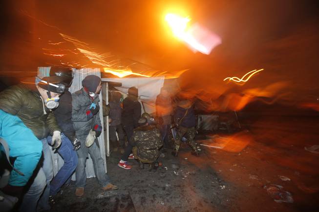 Protesters clash with police, in central Kiev, Ukraine, Monday, Jan. 20, 2014. After a night of vicious streets battles, anti-government protesters and police clashed anew Monday in the Ukrainian capital Kiev. Hundreds of protesters, many wearing balaclavas, hurled rocks and police responded with tear gas.