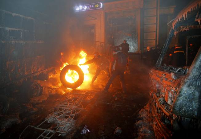 Protesters burn car tires as they clash with police in central Kiev, Ukraine, early Tuesday, Jan. 21, 2014. After a night of vicious street battles, anti-government protesters and police clashed again Monday in Ukraine's capital. Hundreds of protesters, many wearing balaclavas, hurled rocks and stun grenades. Police responded with tear gas.