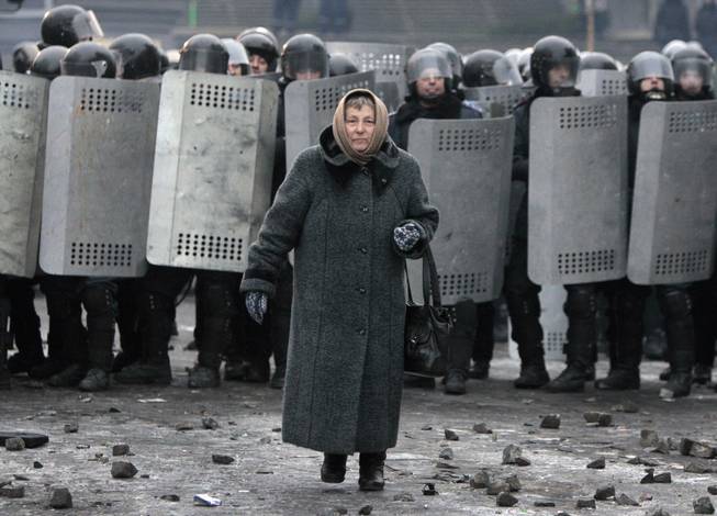 An elderly woman walks from police officers as they block a street during unrest in central Kiev, Ukraine,Tuesday, Jan. 21, 2014. Anti-government protesters have held their ground through a night of violent street clashes in the Ukrainian capital, despite police moving in to dismantle barricades erected in a street leading to government offices. Police attempted to move in on the protest camp early Tuesday, but faced fierce resistance from demonstrators who tossed fire bombs and stones in their direction.