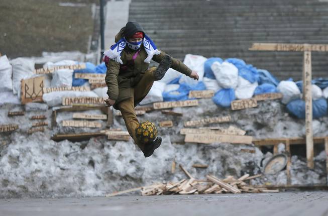 A Pro-European Union activist plays with the ball in front of barricades at the Independence Square in Kiev, Ukraine, Thursday, Dec. 19, 2013. President Vladimir Putin says Russia's $15-billion bailout for Ukraine is driven by a desire to help a partner in a desperate situation and isn't linked to its talks with the European Union.The Kremlin's move comes as Ukrainian President Viktor Yanukovych faces massive street protests over his decision to spike a pact with the EU in favor of closer ties with Russia.