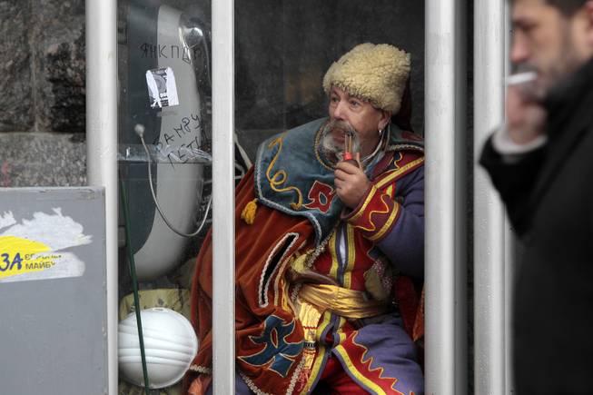 An anti-government protester sits in a telephone booth in Kiev, Ukraine, Friday, Dec. 6, 2013. A leader of the protests gripping Ukraines capital to try to force the governments resignation says the opposition is willing to talk with officials to find a way out of the crisis, but only if the police who violently dispersed demonstrators are punished.