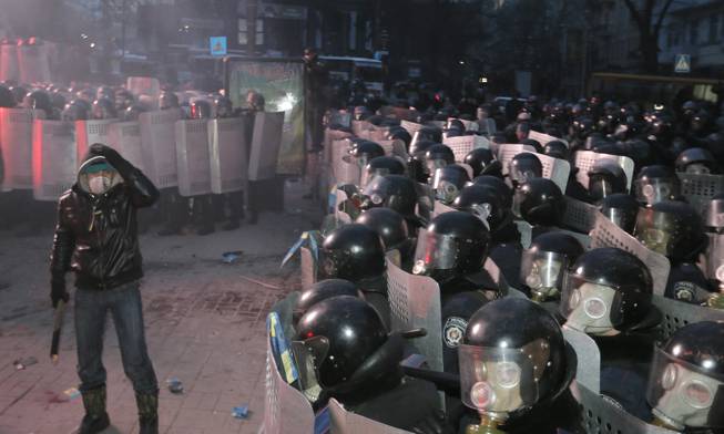 A protester stands in front of riot police in central Kiev, Ukraine, Sunday, Jan. 19, 2014. Hundreds of protesters on Sunday clashed with riot police in the center of the Ukrainian capital, after the passage of harsh anti-protest legislation last week seen as part of attempts to quash anti-government demonstrations. A group of radical activists began attacking riot police with sticks, trying to push their way toward the Ukrainian parliament building, which has been cordoned off by rows of police and buses.