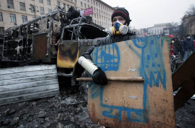 A pro-European Union activist stands in front of a barricade during clashes with police in central Kiev, Ukraine, Tuesday, Jan. 21, 2014. Anti-government protesters have held their ground through a night of violent street clashes in the Ukrainian capital, despite police moving in to dismantle barricades erected in a street leading to government offices. Police attempted to move in on the protest camp early Tuesday, but faced fierce resistance from demonstrators who tossed fire bombs and stones in their direction.