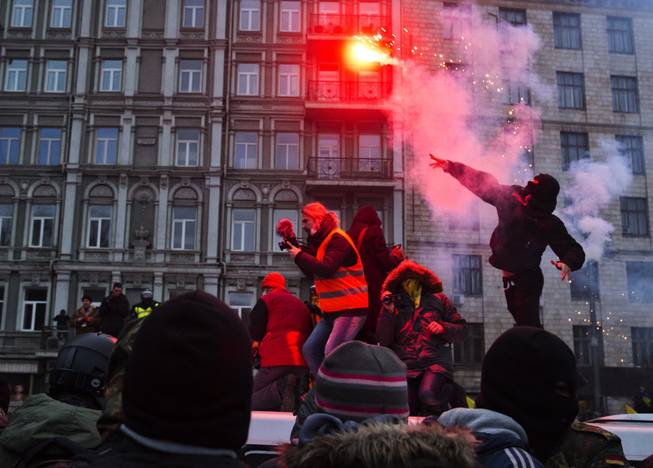 A protester throws a burning flare during clashes with police, in central Kiev, Ukraine, Sunday, Jan. 19, 2014. Hundreds of protesters on Sunday clashed with riot police in the center of the Ukrainian capital, after the passage of harsh anti-protest legislation last week seen as part of attempts to quash anti-government demonstrations. The violent scenes further escalated this ex-Soviet republic's political crisis and showed a rift among opposition leaders, one of whom fought bravely to stop the violence, while others condemned the events from afar.