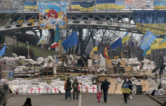 People walk past a barricade in Independence Square in Kiev, Ukraine, Monday, Dec. 23, 2013. Ukraine has been stricken with mass protests for over a month. Protesters are demanding President Viktor Yanukovych's resignation over his decision to ditch a pact with the European Union in favor of closer ties with Russia.