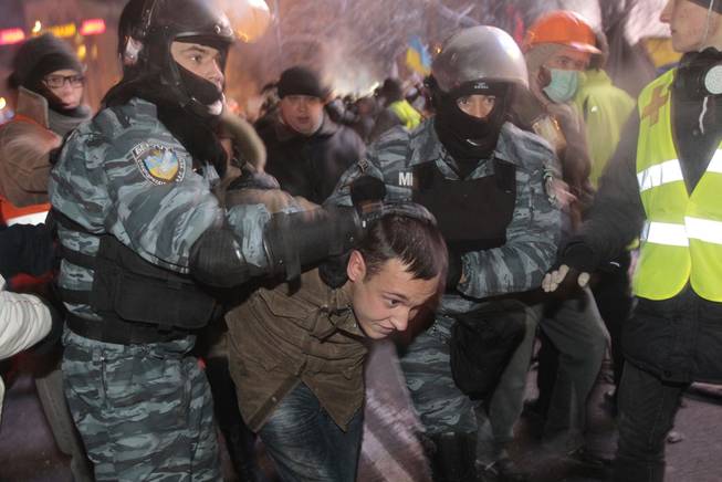 Ukrainian riot policemen pull a Pro-European Union activist out form a tent camps on the Independence Square in Kiev, Ukraine, Wednesday, Dec. 11, 2013. Security forces clashed with protesters as they began tearing down opposition barricades and tents set up in the center of the Ukrainian capital early Wednesday, in an escalation of the weeks-long standoff threatening the leadership of President Viktor Yanukovych.
