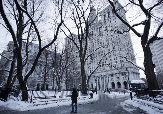 A pedestrian passes through City Hall Park and the Municipal Building, center, Wednesday, Jan. 22, 2014, in New York. The Northeast struggled to dig out of a winter storm Wednesday that swirled up the coast, disrupting government work in Washington and leaving behind bitter cold that sapped fuel supplies.