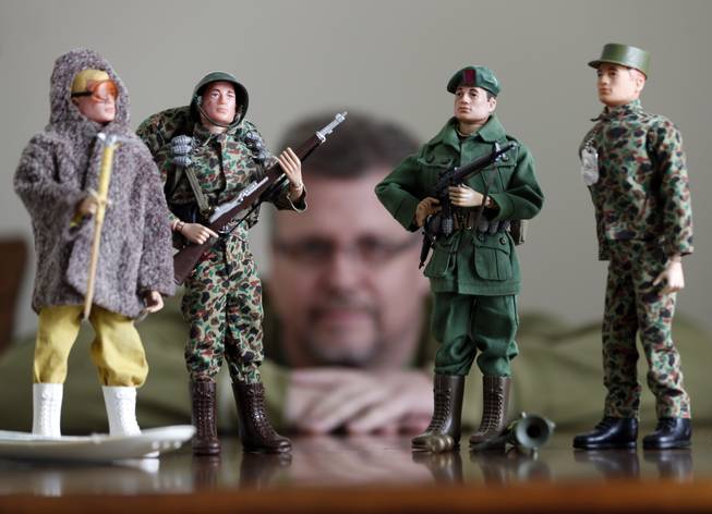 In this Jan. 31, 2014, photo Tearle Ashby poses with some of his G.I. Joe action figures in Niskayuna, N.Y. A half-century after the 12-inch doll was introduced at a New York City toy fair, the iconic action figure is being celebrated by collectors with a display at the New York State Military Museum, while the toy's maker plans other anniversary events to be announced later this month.