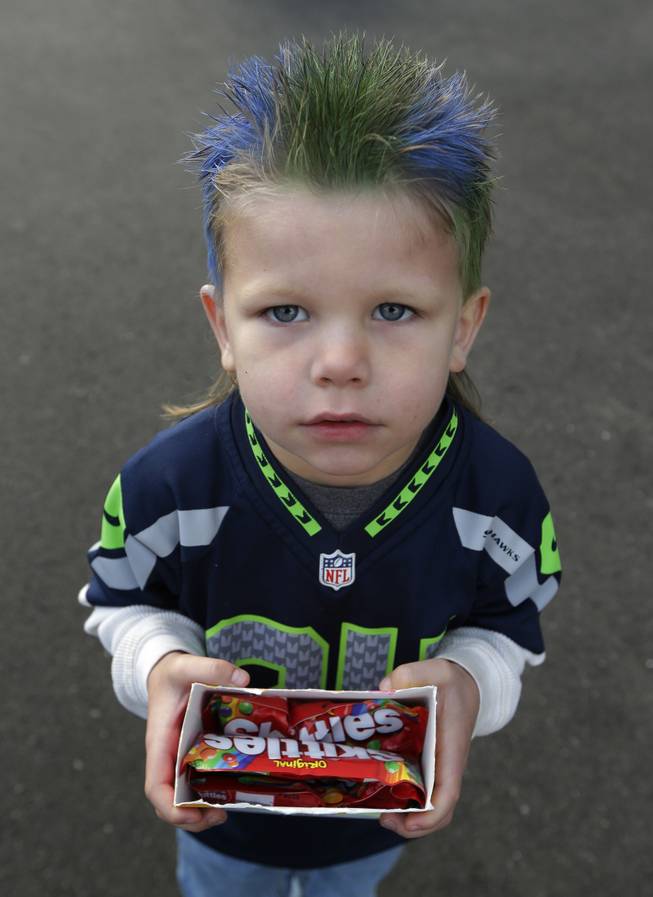 Seattle Seahawks fan Oskar Van De Plasch, 4, poses for a photo as he carries an offering of the Skittles candy favored by Seattle Seahawks running back Marshawn Lynch as he waits at the Seahawks' headquarters in Renton, Wash., Sunday, Jan. 26, 2014, to see players and coaches board buses for their flight to play the Denver Broncos in the NFL Super Bowl XLVIII football game in East Rutherford, N.J.