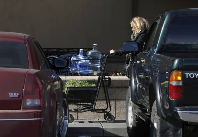 In this photo taken Tuesday, Feb. 4, 2014, Kathleen Camp leaves a local market with bottled water in Willits, Calif. With area reservoirs holding less than a 100-day supply of water, city leaders have banned lawn watering, car washing and mandated all residents to cut water use.