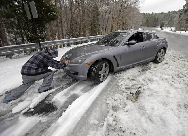 Passerby Leo Cruz helps push a car from the frozen roadside in Chapel Hill, N.C., Thursday, Feb. 13, 2014. The owner abandoned the car overnight during the storm. The National Weather Service issued a winter storm warning lasting into Thursday covering 95 of the state's 100 counties.