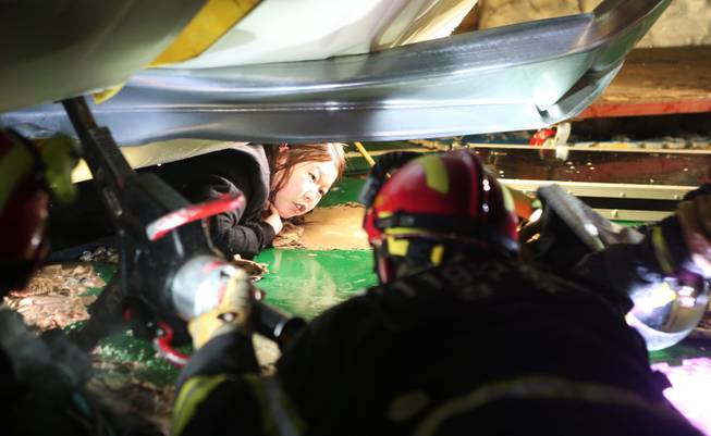 A woman trapped in the rubble of a collapsed resort building waits to be rescued in Gyeongju, South Korea, Monday, Feb. 17, 2014. South Korean police and news reports say that dozens of university students are feared trapped after a buildingis roof collapsed because of recent heavy snowfall.