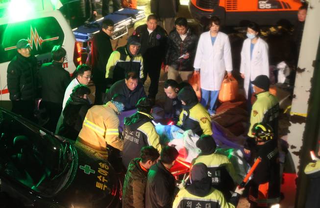 Rescue workers carry a victim, medical condition unknown, from a collapsed resort building in Gyeongju, South Korea, Monday, Feb. 17, 2014. South Korean police and news reports say that dozens of university students are feared trapped after a buildingis roof collapsed because of recent heavy snowfall.