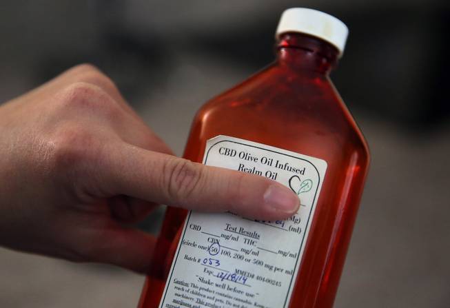 In this Feb. 7, 2014 photo, Aileen Burger holds up a bottle of cannabis-infused oil used as medicine for her 4-year-old daughter Elizabeth, who suffers from severe epilepsy and is receiving the experimental treatment with a special strain of medical marijuana, at her home in Colorado Springs, Colo.