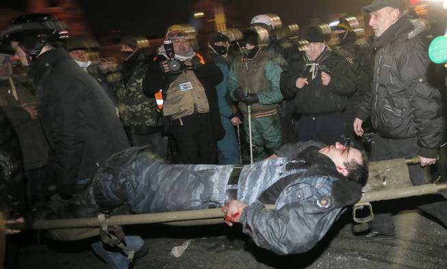 Anti-government protesters carry a wounded policemen during clashes with riot police in Kiev's Independence Square, the epicenter of the country's current unrest, Kiev, Ukraine, Wednesday, Feb. 19, 2014. Thousands of angry anti-government protesters clashed with police in a new eruption of violence following new maneuvering by Russia and the European Union to gain influence over this former Soviet republic.