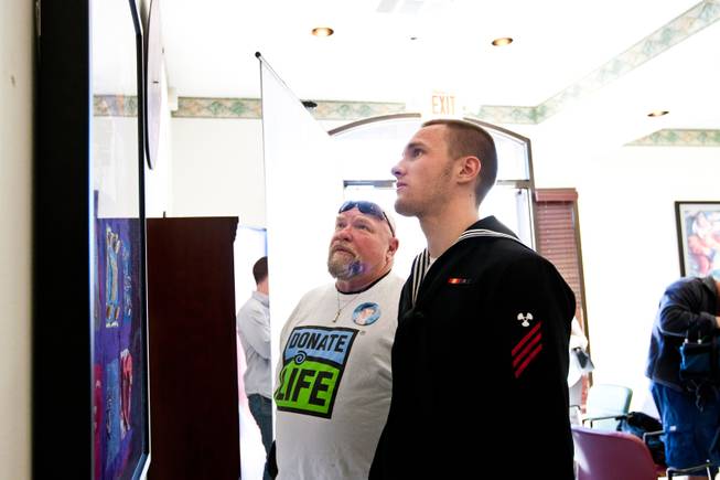 Kevin and Don Brill, right, (brother and father respectively) admire a homemade, patchwork quilt hung in honor of Aric Brill during a ceremony celebrating the life of 16-year-old Aric Michael Brill, who donated six organs following his homicide five years ago, at the UMC Transplant Center Friday, February 21, 2014.
