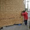 Photo: A passer-by peers into a plywood barrier now prote Photo: A passer-by peers into a plywood barrier now prote